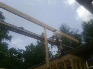 Carpenter setting a ridge beam over a new addition frame — Ice Dam Removal by Roofing Brothers in Goshen